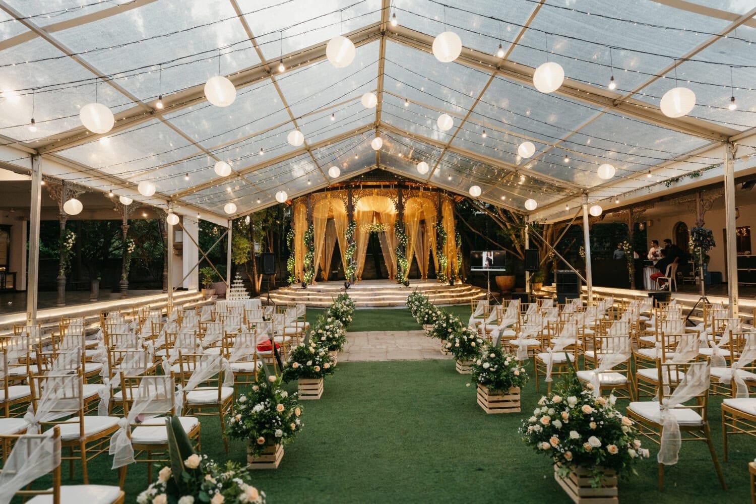 Event lawn under a glass canopy, set with chairs and flowers